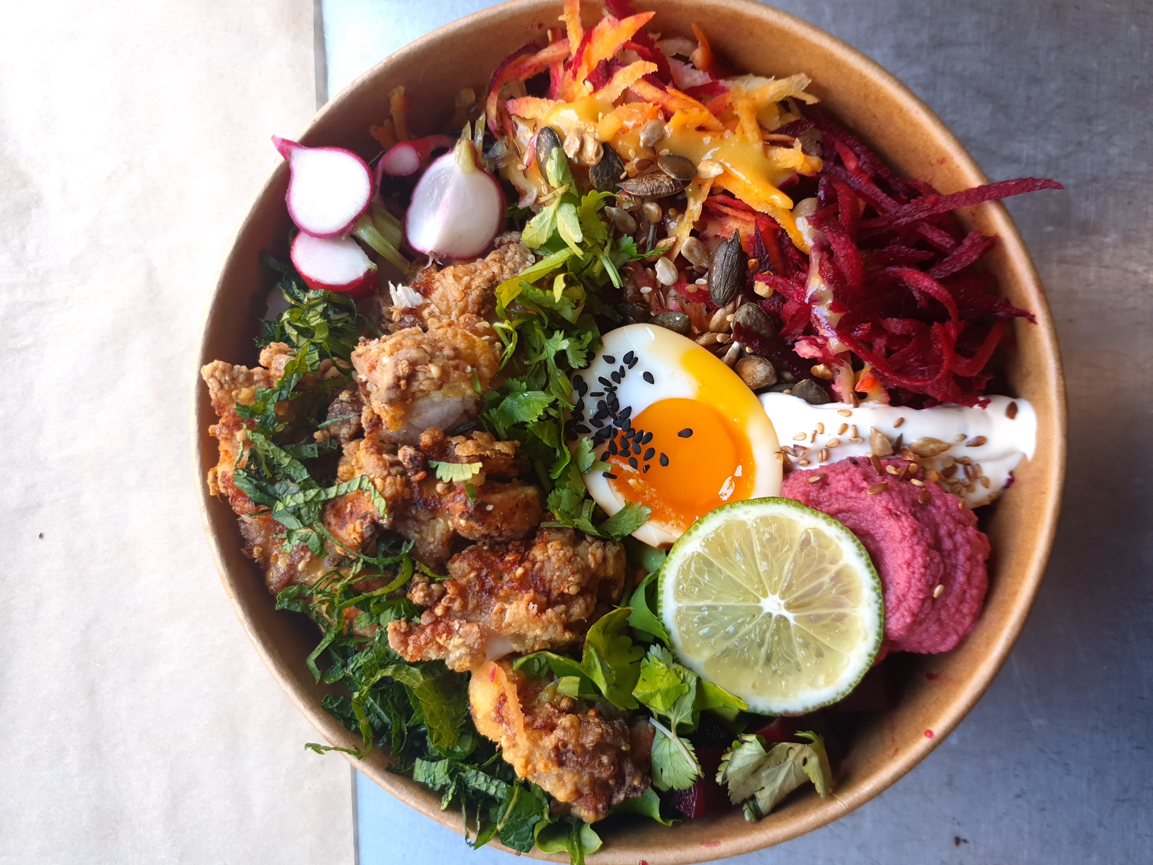 Colourful nourish bowl with crispy chicken and fresh toppings