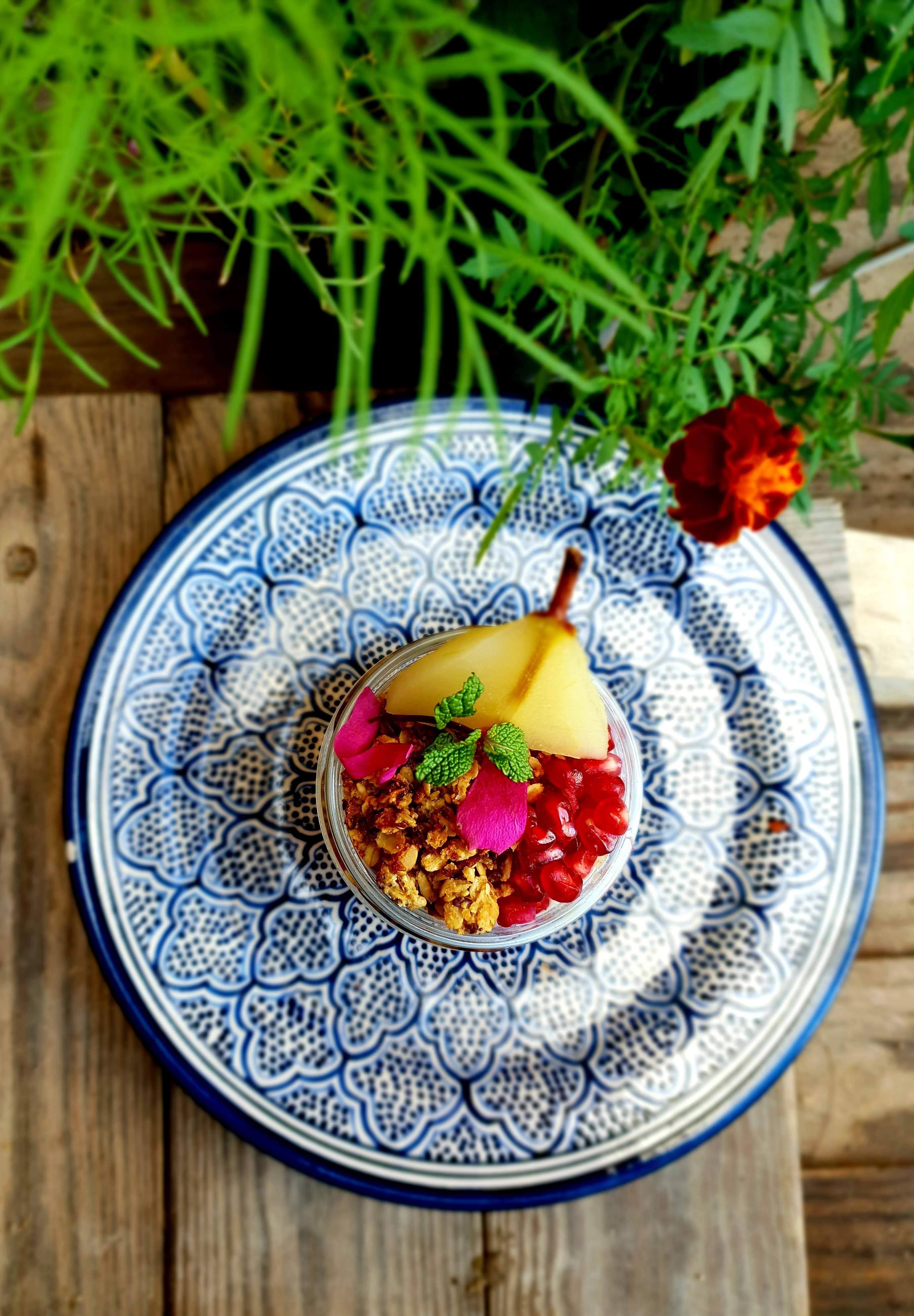 Poached pear with granola on a decorative plate